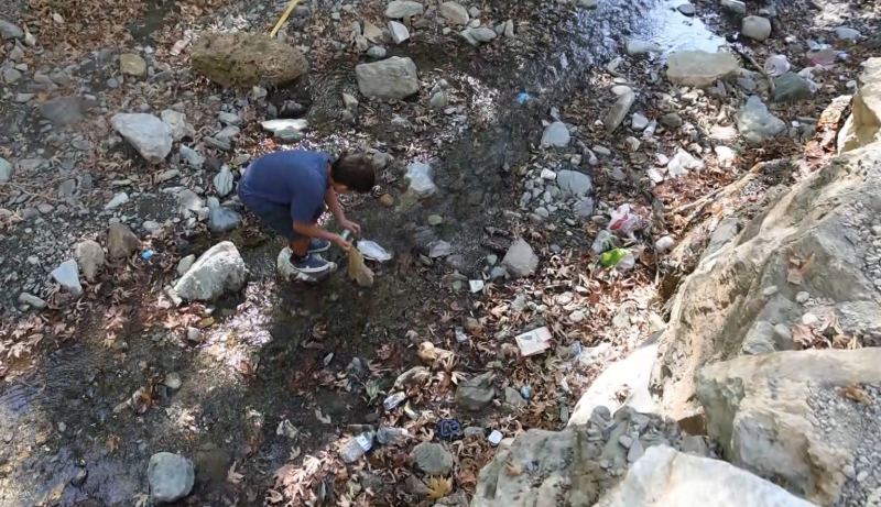ADANA’NIN FEKE İLÇESİNDE ÇINAR AĞAÇLARININ GÖLGESİNDE, DOĞAL KAYNAK SUYUNUN BULUNDUĞU GEÇİRİMOLUK MESİRE ALANI’NA ASILAN "ÇÖP ATAN EŞEKTİR" YAZILI TABELA DİKKAT ÇEKERKEN, ÇEVREDEKİ ÇÖPLERE TEPKİ GÖSTEREN ÇOCUKLAR DERE YATAĞINDAKİ ATIKLARI TOPLADI.